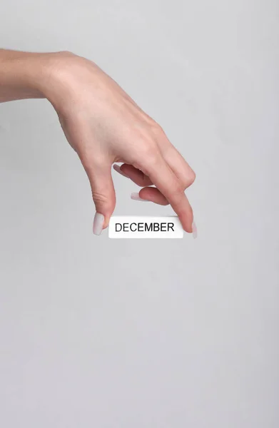 Mão Mulher Segura Placa Branca Madeira Com Inscrição Dezembro Fundo — Fotografia de Stock