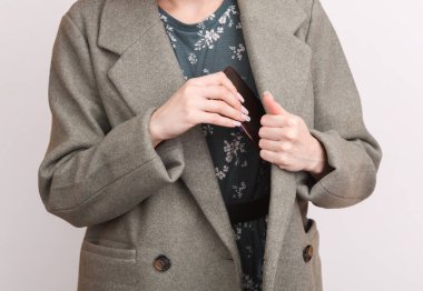 Beyaz arka plana yün ceket cebine akıllı telefon koyan kadın