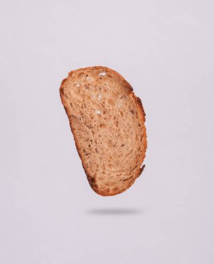 Bir parça çavdar ekmeği, gölgeli gri arka planda uçuyor.