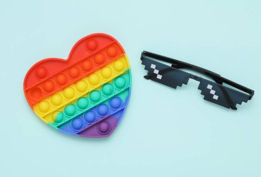 Pikselleştirilmiş 8 bit güneş gözlüğü ve pastel arka planda anti-stres oyuncağı.