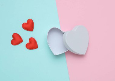 Pembe mavi pastel arka planda kırmızı kalpleri olan kalp şeklinde boş beyaz bir kutu.