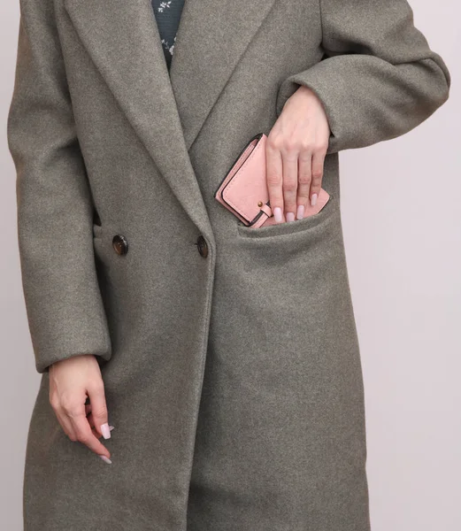 Woman putting purse in wool coat pocket on white background