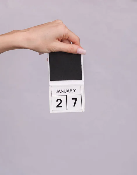 stock image Female hand holding wooden calendar with date January 27 on gray background