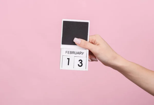 stock image Female hand holding wooden calendar with date February 13 on pink background