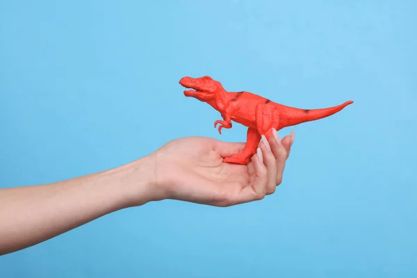 Brinquedo Plástico Tyrannosaurus Rex Mão Feminina Sobre Fundo Azul — Fotografia de Stock