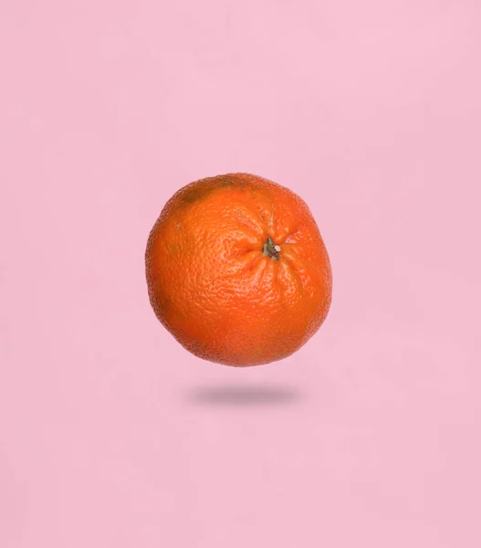 带阴影的粉色背景上的成熟橘子飘扬 — 图库照片