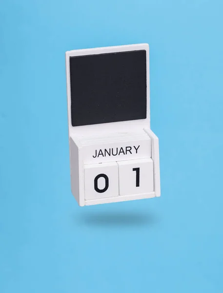 stock image Wooden calendar with january 01 date levitating on a blue background. New Year