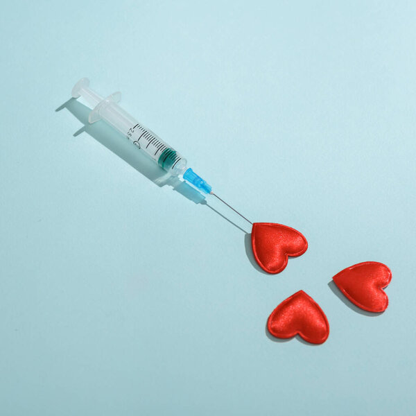 Syringe with hearts on a blue background