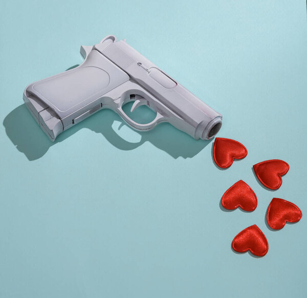 Creative layout. No war. Pistol with hearts on a blue background