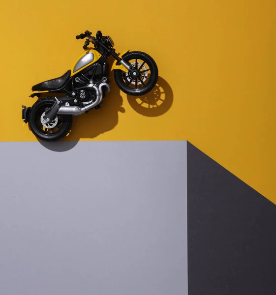 Toy motorbike on a paper cube. Optical illusion. Geometric composition. Minimalistic creative layout