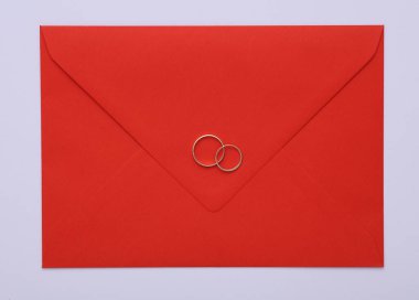 Gri zemin üzerinde altın halkalar olan kırmızı zarf.