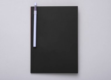 Gri arka planda siyah kapaklı ve kalemli defter