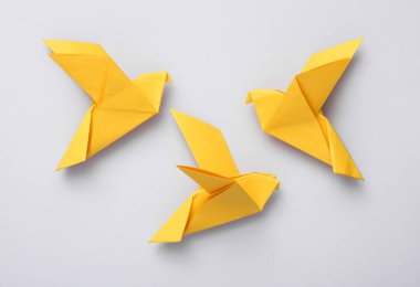 Sarı origami güvercinleri gri arka planda. Barış sembolü, savaş yok.