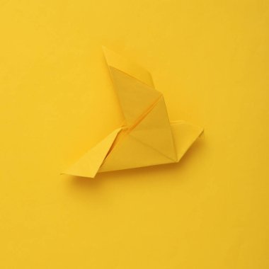 Sarı arka planda sarı origami güvercini. Barış sembolü, savaş yok.
