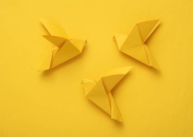 Sarı arka planda sarı origami güvercinleri. Barış sembolü, savaş yok.