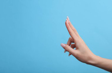 Mavi arka planda kartviziti tutmak için boş alan tutan kadın el modeli