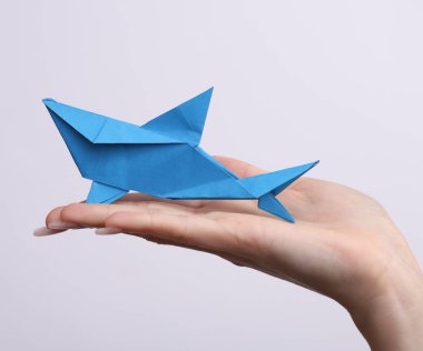 Kadın el, beyaz arka planda origami köpekbalığı tutuyor. Hobi, yaratıcılık