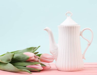 Pastel zemin üzerinde laleler olan beyaz seramik çaydanlık