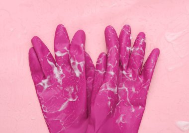 Pembe arka planda köpük kaplı lastik eldivenler. Temizlik kavramı