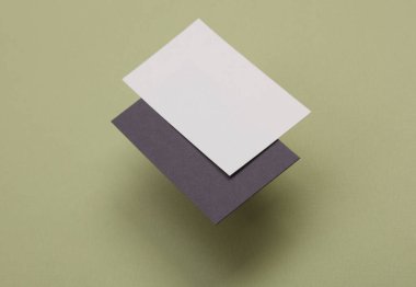 Yeşil arka planda damgalamak için gri ve beyaz kartvizitler. Sunumlar ve kurumsal kimlik için yaratıcı bir model