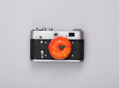 Gri arka planda dekoratif bir balkabağı olan kamera. En az cadılar bayramı düzeni