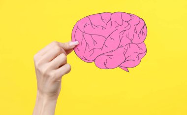 Sarı arka planda kağıt kesiği bir beyni tutan