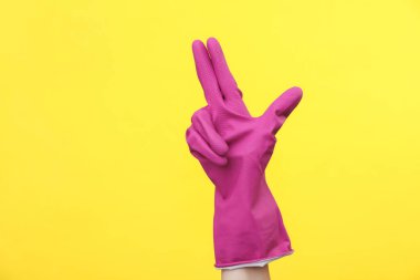 Sarı arka planda mor kauçuk temizleme eldiveni. Ev temizliği ve temizlik konsepti