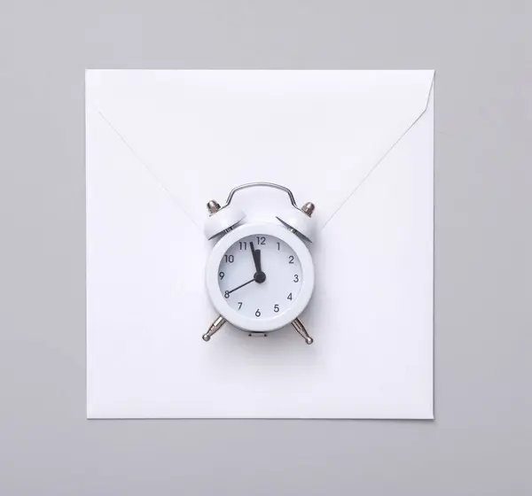 Gri Zemin Üzerinde Alarm Saati Olan Beyaz Zarf — Stok fotoğraf