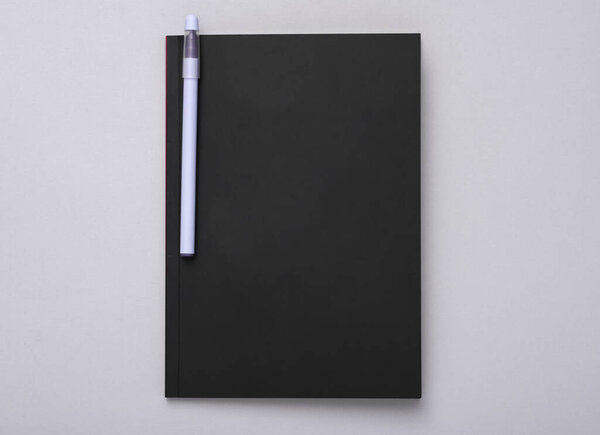 Notebook with black cover and pen on gray background