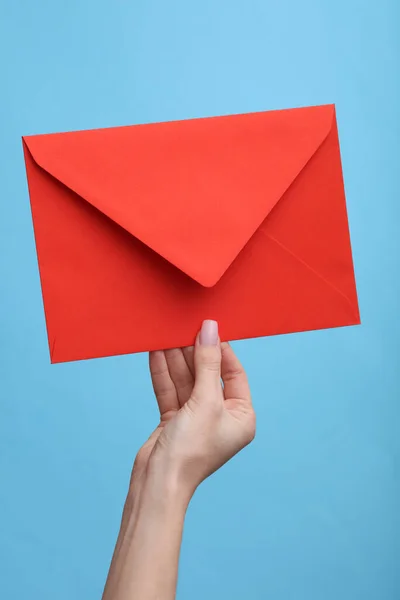 Vrouwenhand Met Een Rode Envelop Een Blauwe Achtergrond — Stockfoto