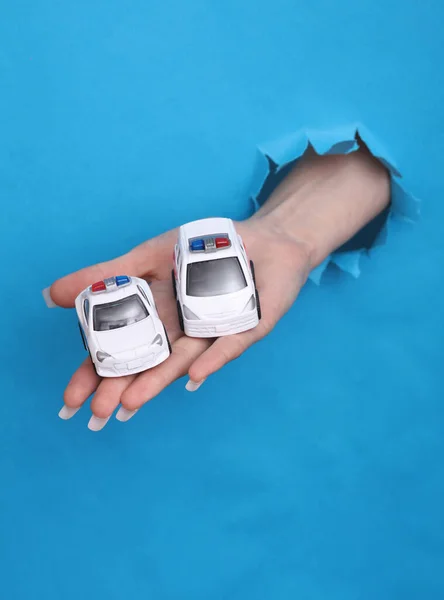 Weibliche Hand Hält Spielzeug Krankenwagen Und Polizeiauto Durch Zerrissenes Loch — Stockfoto