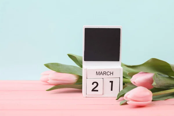 Block wooden calendar with the date March 21 and tulips on a pastel background. Spring composition