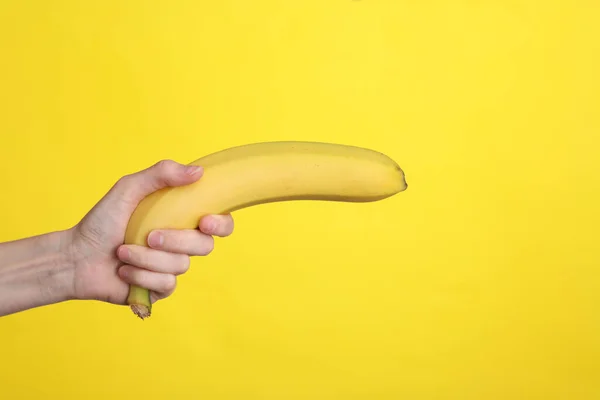 Mano Femenina Sostiene Plátano Como Arma Sobre Fondo Amarillo — Foto de Stock