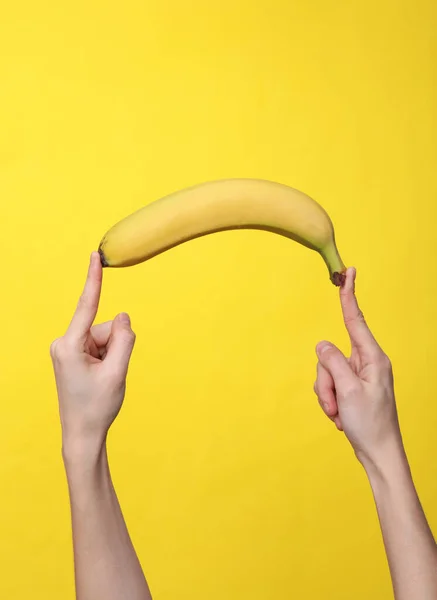 Γυναικεία Χέρια Που Κρατούν Μια Μπανάνα Κίτρινο Φόντο — Φωτογραφία Αρχείου
