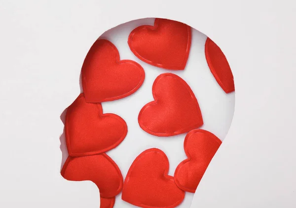 Human face cut out of paper hole with hearts on white background. Valentine\'s day, love concept