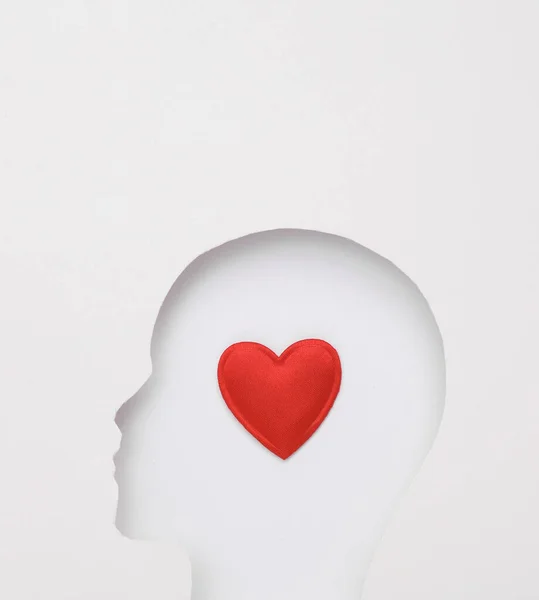 Human face cut out of paper hole with heart on white background. Valentine\'s day, love concept