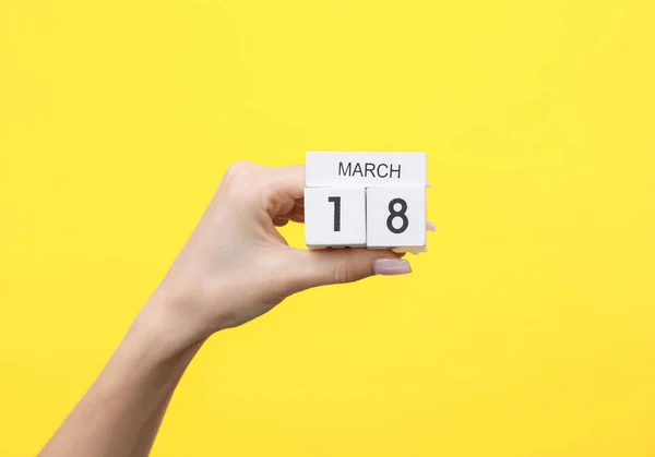 Ręka Kobiety Trzyma Drewniany Kalendarz Bloku Datą Marca Żółtym Tle — Zdjęcie stockowe