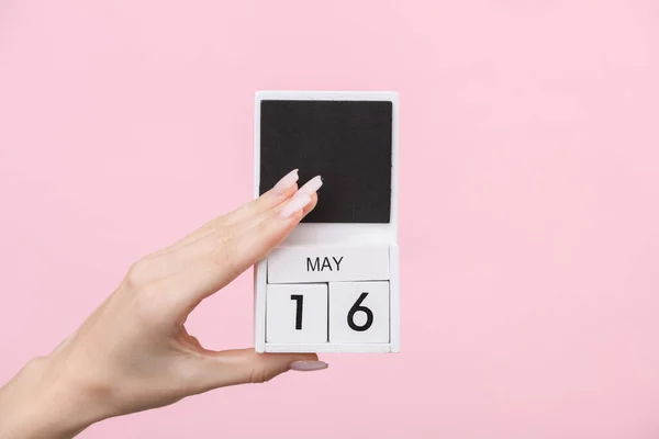 stock image Block calendar with date may 16 in female hand on pink background