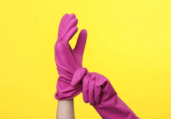 黄色の背景に紫色のゴム製のクリーニング手袋で手 清掃とハウスキーピングのコンセプト — ストック写真