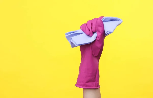 黄色の背景にラグを保持紫色のゴムクリーニング手袋で手 清掃とハウスキーピングのコンセプト — ストック写真