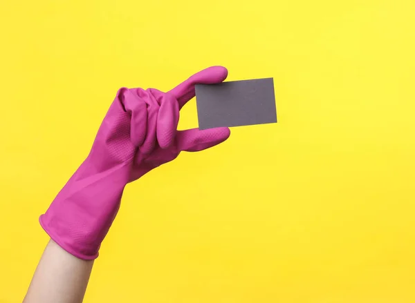 手拿着紫色橡胶清洁剂手套 手拿着黄色背景的名片 家庭清洁和内务管理概念 — 图库照片