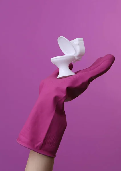 Рука Фиолетовой Резиновой Чистящей Перчатке Миниатюрным Туалетом Фиолетовом Фоне — стоковое фото