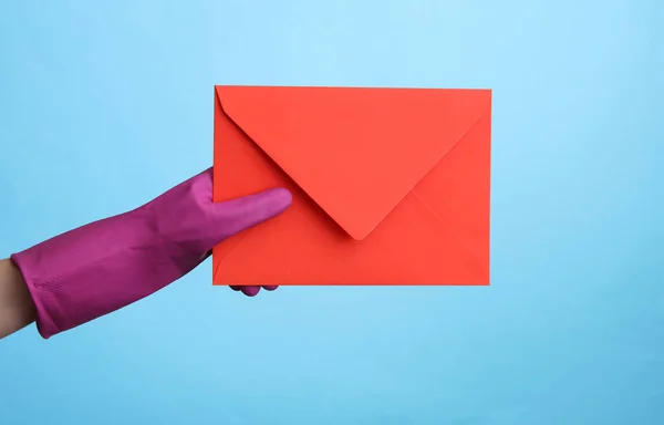 青の背景に封筒を保持紫色のゴムクリーニング手袋で手 — ストック写真