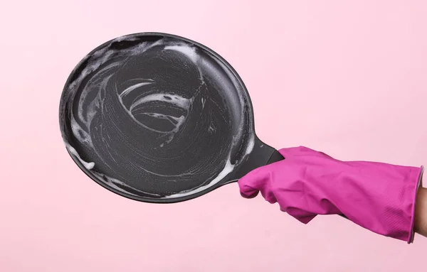stock image Hands in rubber gloves wash frying pan with foam on pink background