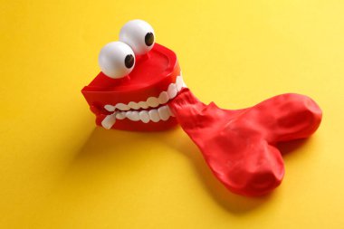 Şakacı çene, sarı arka planda kırmızı kalp şeklindeki balonu şişirir. Aşk konsepti