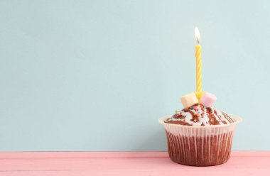 Pastel arka planında yanan bir mum olan kek. Doğum günü kavramı