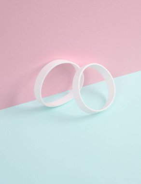 Mavi-pembe renkli arka planda beyaz silikon bilezikler.