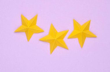 Pastel arka planda üç origami yıldızı. Hizmet derecesi