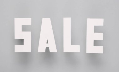 Gri arka planda kağıttan kesilmiş satılık kelimeler