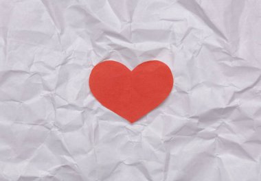 Kırmızı kağıt buruşmuş kağıtta kalbi keser. Aşk konsepti